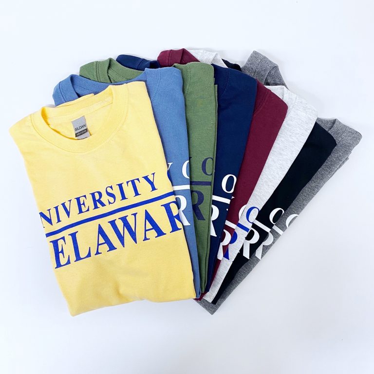 Swirled pile of University of Delaware Skittles Short Sleeve Shirts in a variety of darker colors